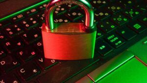 Padlock resting on a computer keyboard under red and green light.
